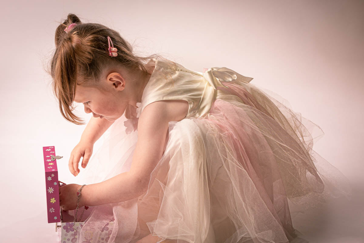“Little ballerina opening a musical jewellery box in a soft pink ballet dress”