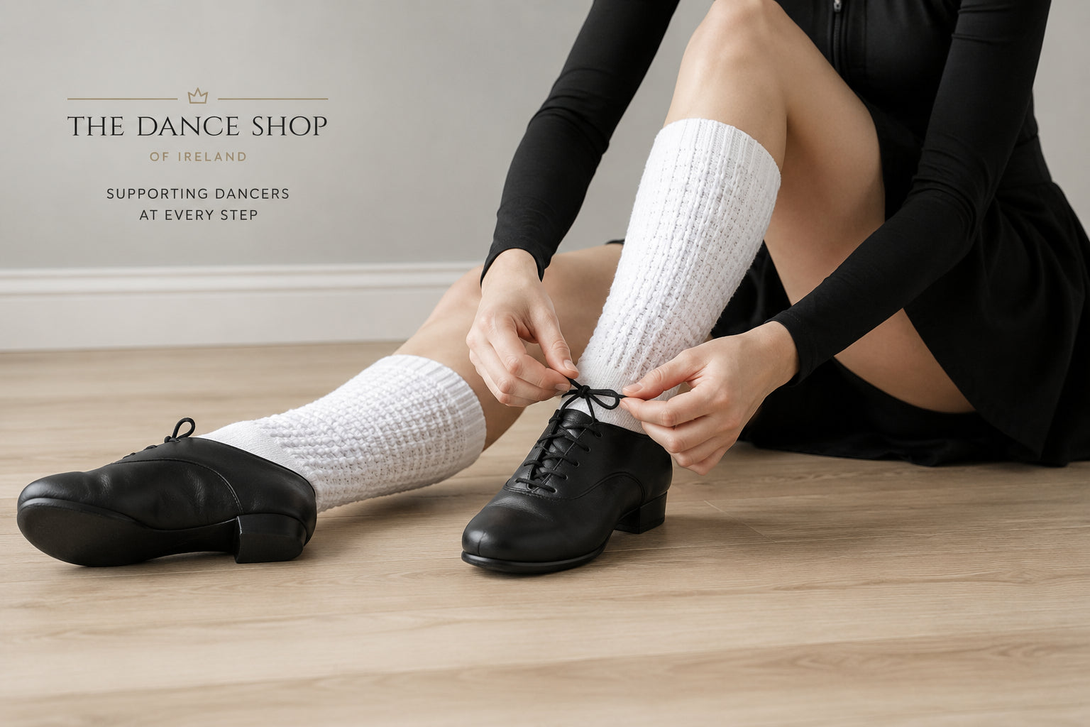 Irish dancer tying black Irish dancing shoes on a wooden dance floor