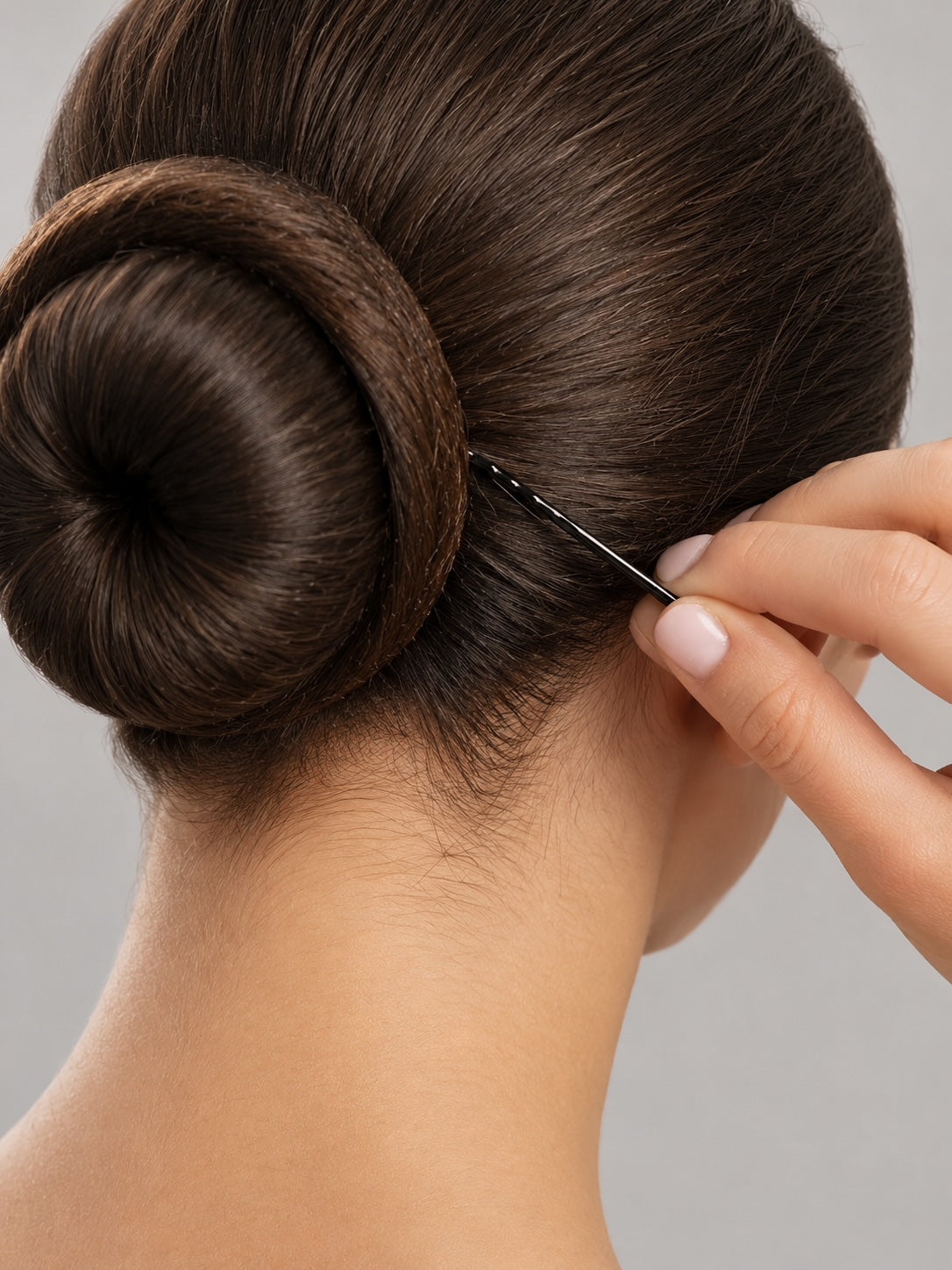 Close-up of a ballet bun secured with a black bobby pin for dance performance hair styling