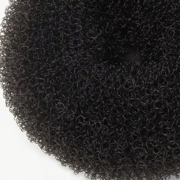 Close-up texture detail of black ballet bun doughnut hair accessory on light grey background