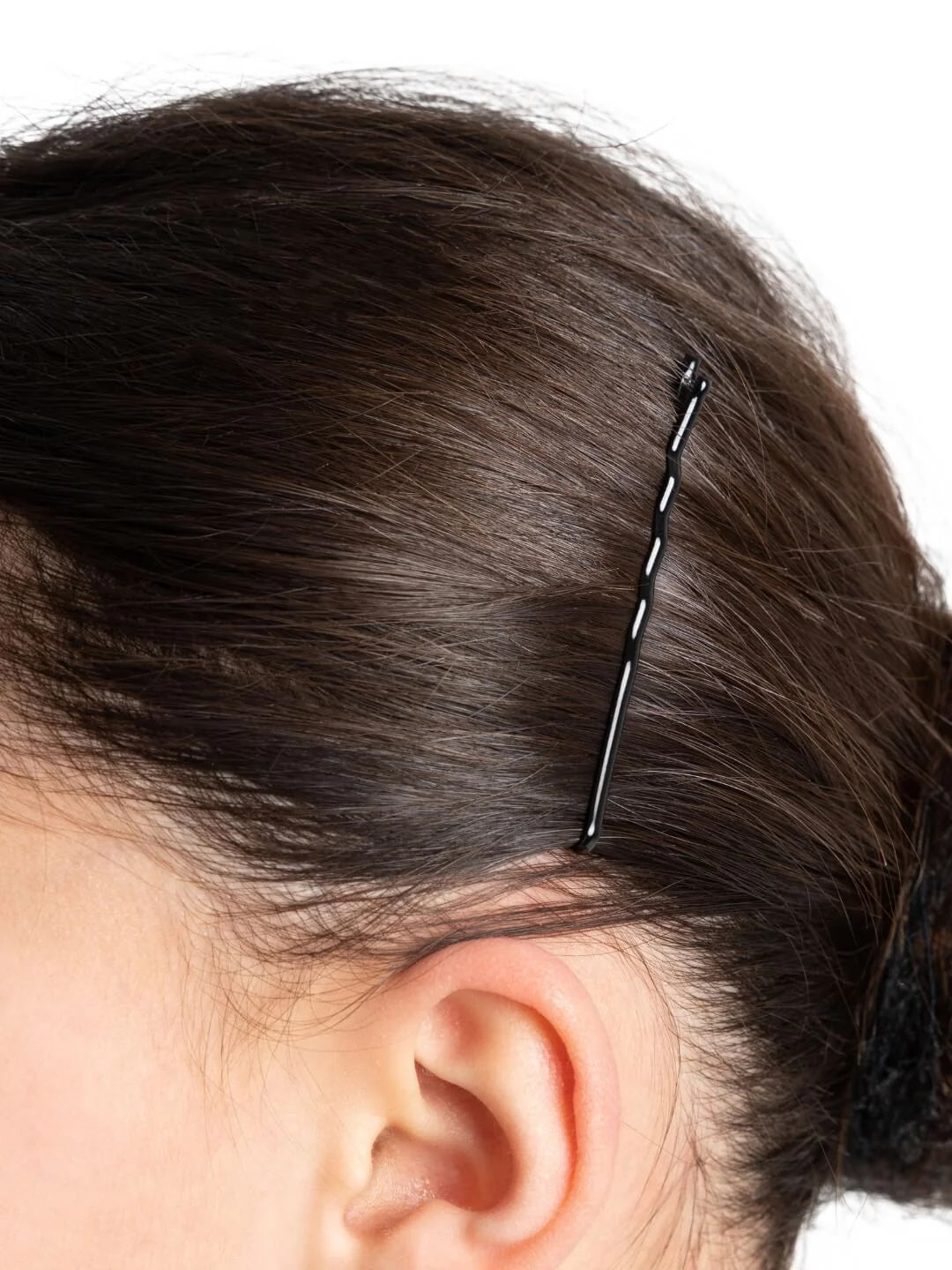 “Close-up of a black bobby pin securing smooth ballet performance hair