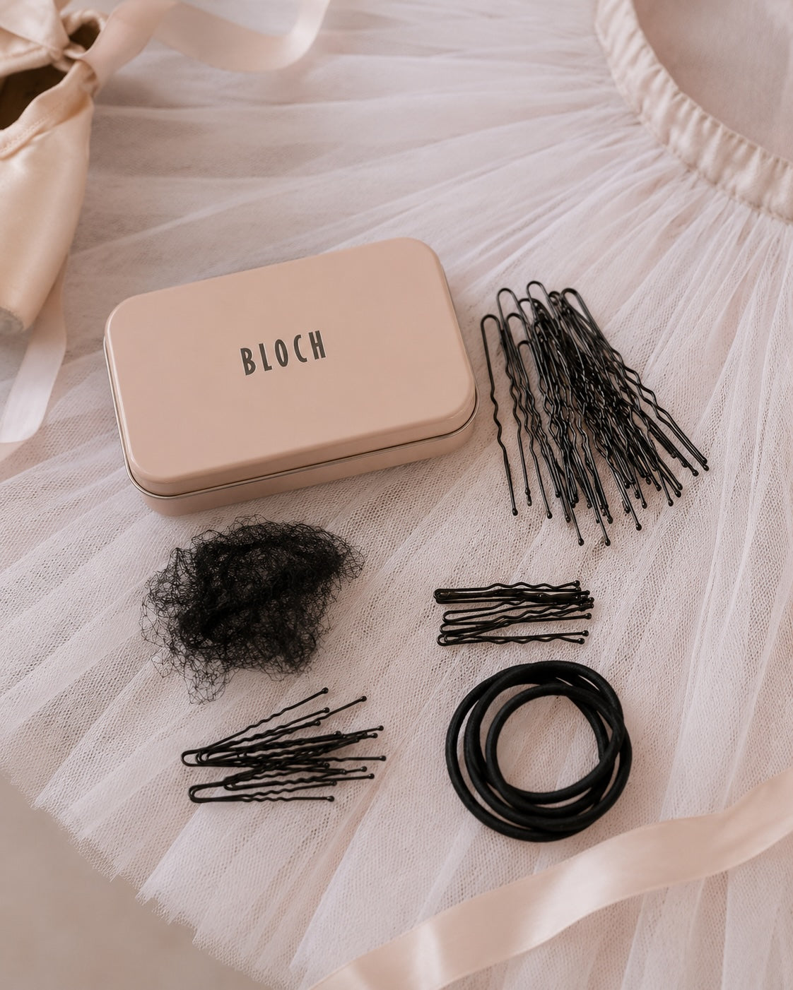 “Bloch ballet hair kit with bun pins, hair net and elastics styled on soft pink ballet tutu fabric”