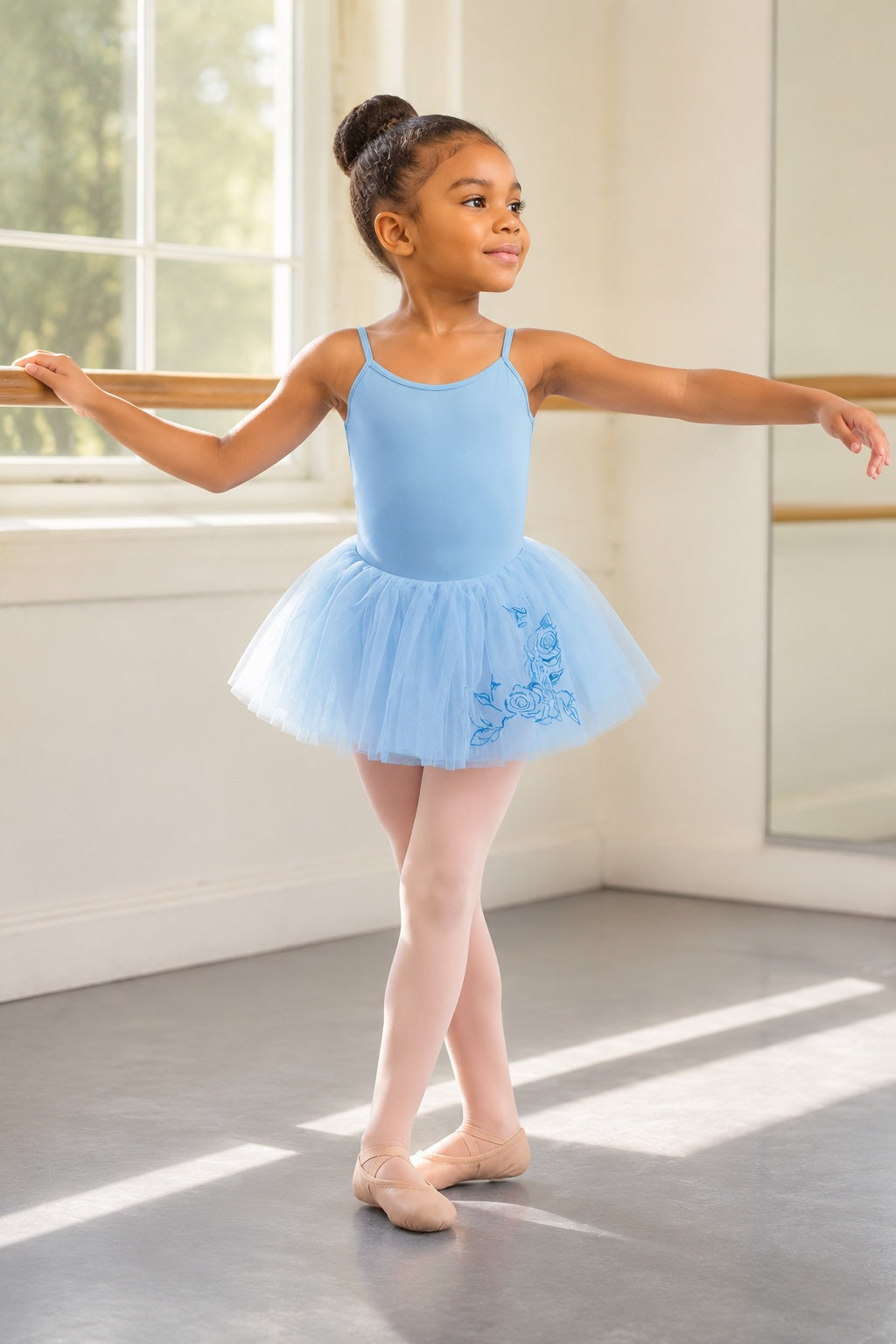 Young ballet dancer wearing a blue Bloch rose embroidered tutu skirt in a ballet studio
