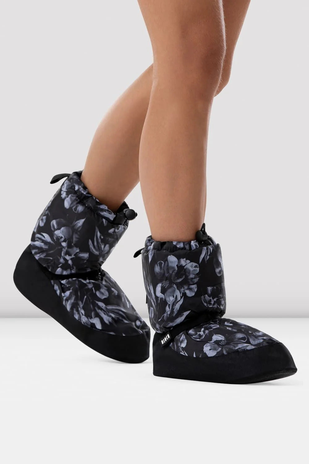 Bloch black floral warm-up bootie shown from the side with adjustable ankle strap and drawstring cuff