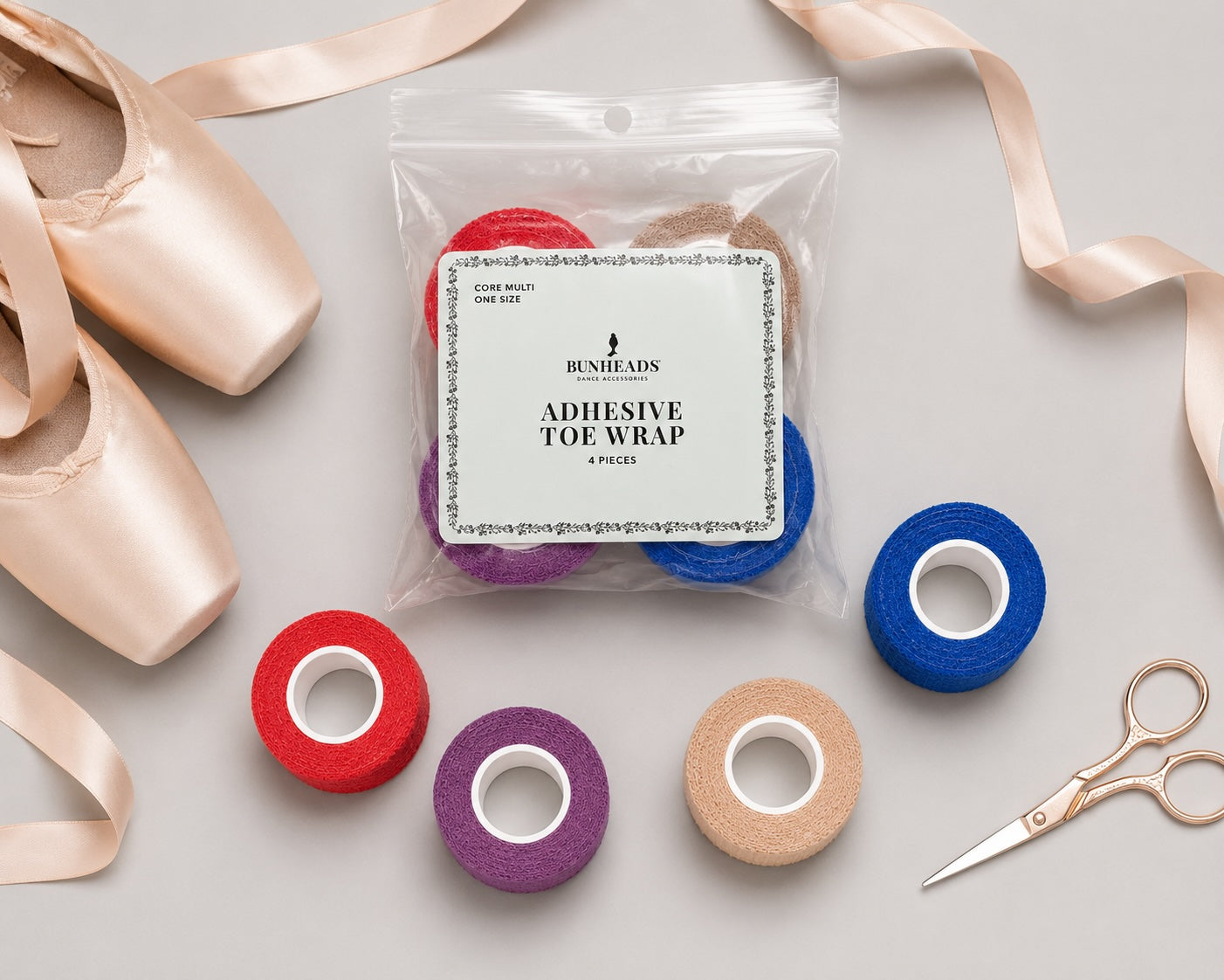 Bunheads Adhesive Toe Wrap Core Multi pack with colourful toe wrap rolls, pointe shoes, ribbons and ballet accessories on a light grey background.