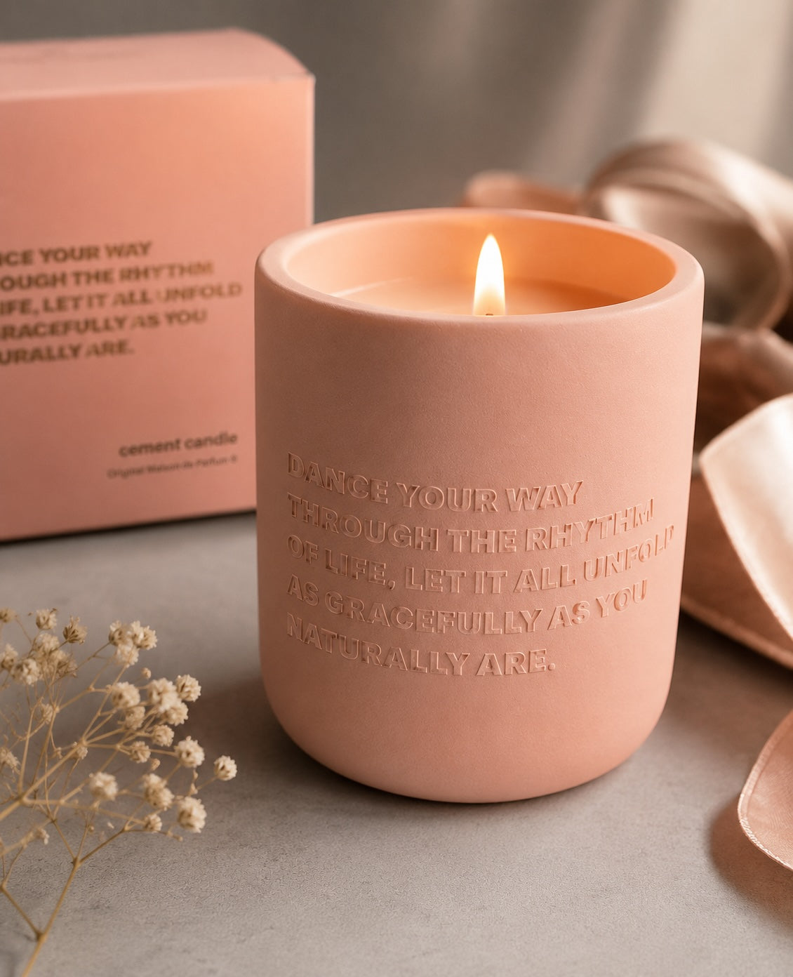 Close-up of lit pink Dance Your Way cement candle with soft warm lighting and elegant embossed detail.