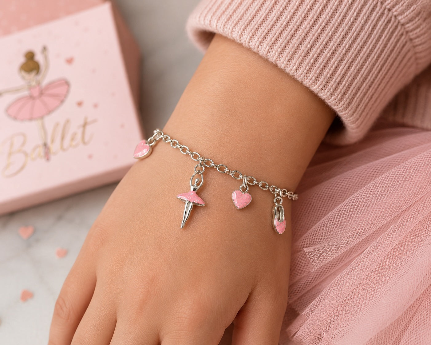 Young dancer wearing pink ballerina hearts charm bracelet with silver chain and ballet-themed charms