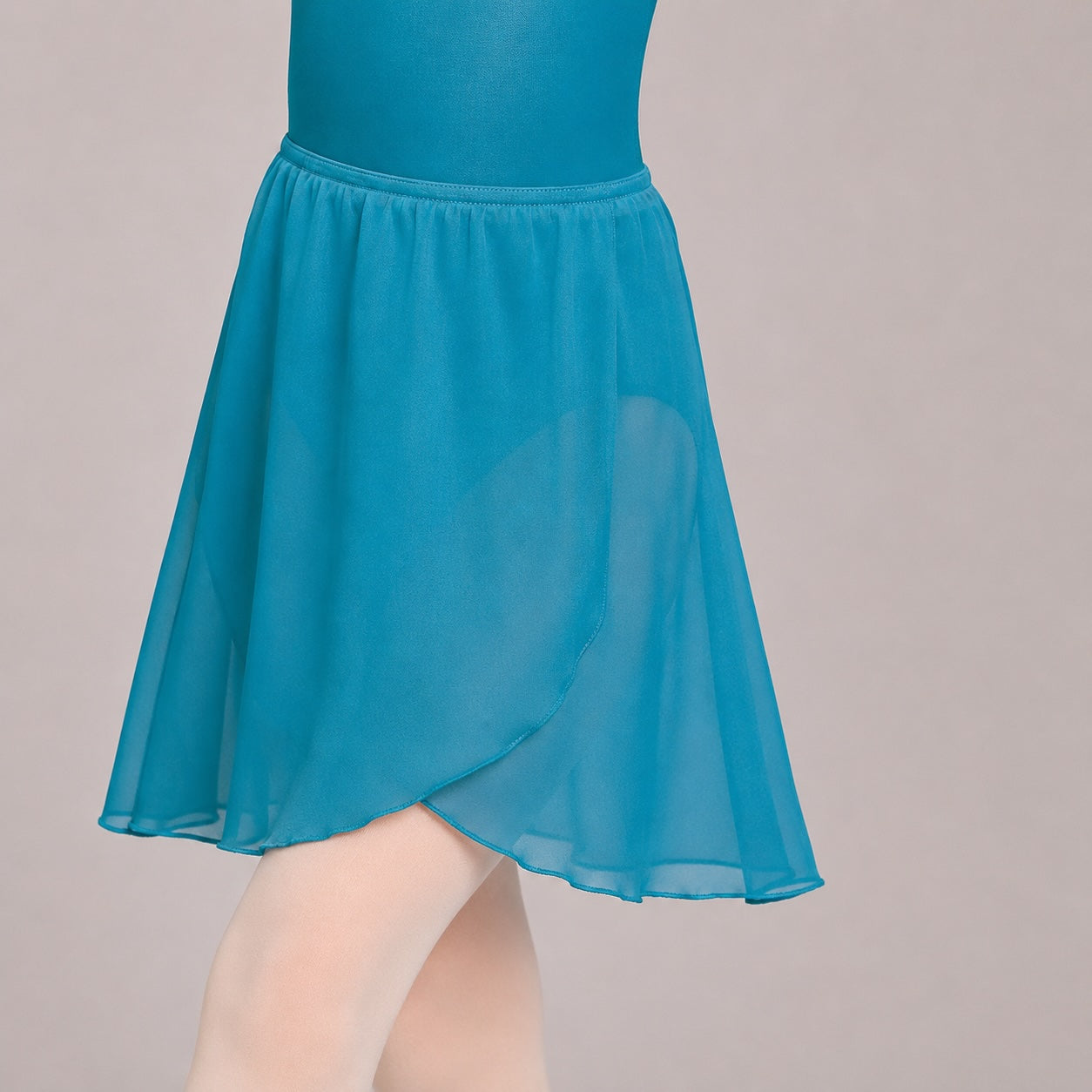 Close-up detail of the chiffon fabric and waistband on the 1st Position marine ballet wrap skirt over a teal ballet leotard.