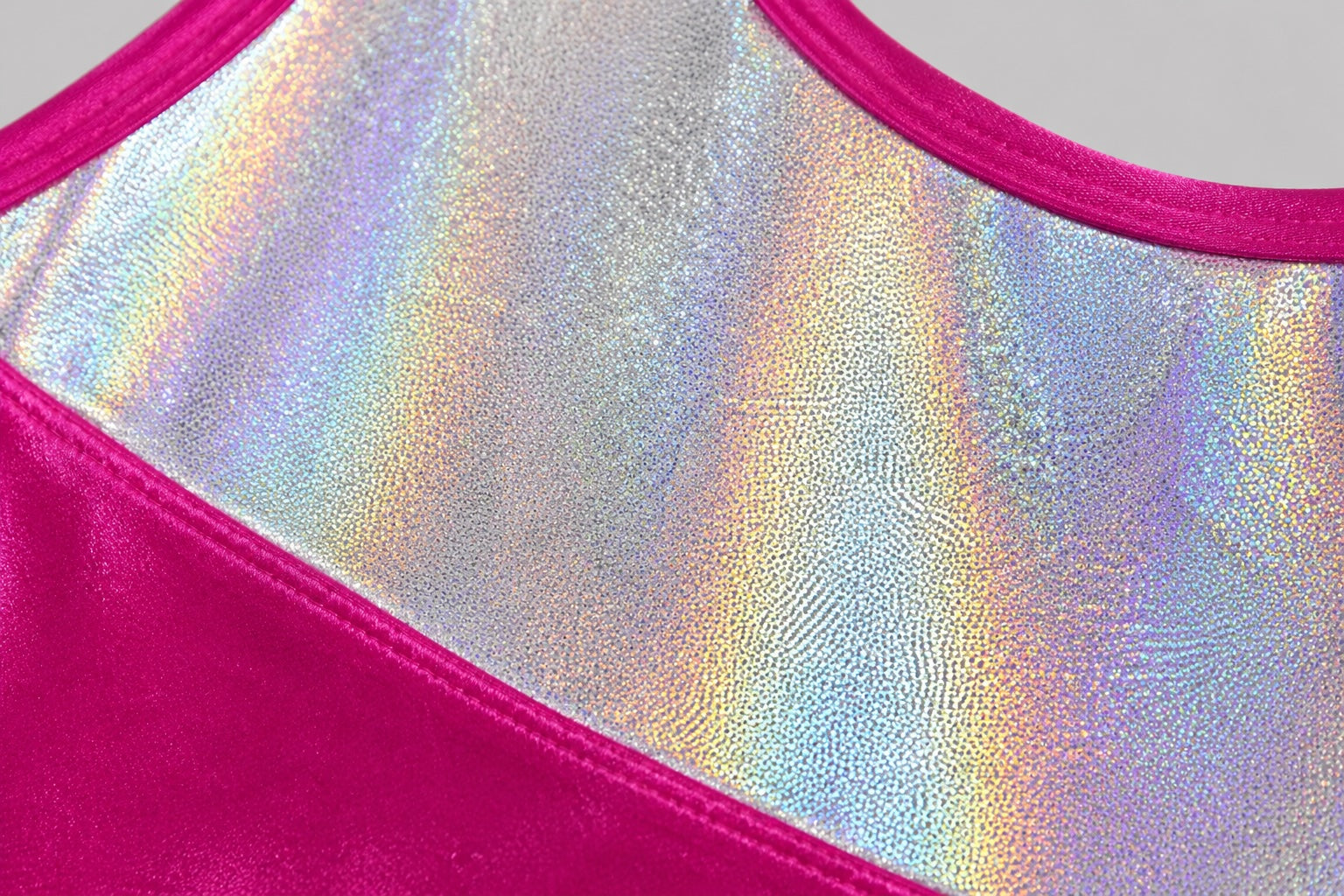 Close-up detail of the silver hologram panel on the 1st Position Taylor GYM007 girls gymnastics leotard showing the shimmering iridescent finish and reflective texture on a light grey background