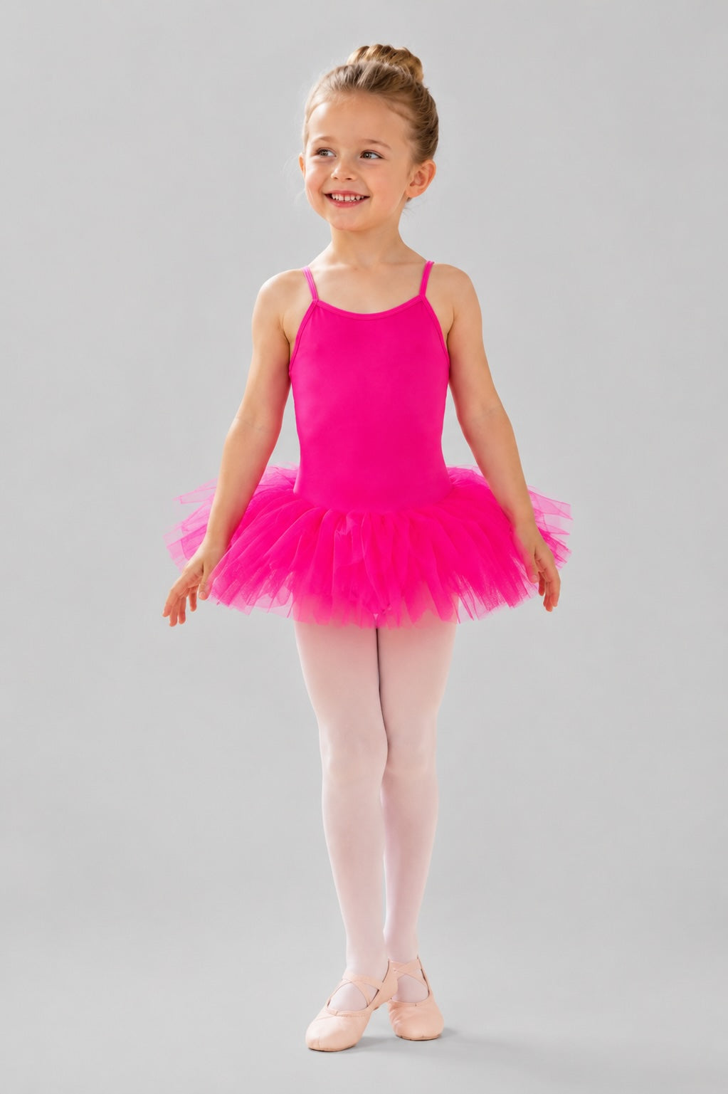 Girls pink 5 layer ballet tutu dress by 1st Position shown on a young ballerina against a light grey background