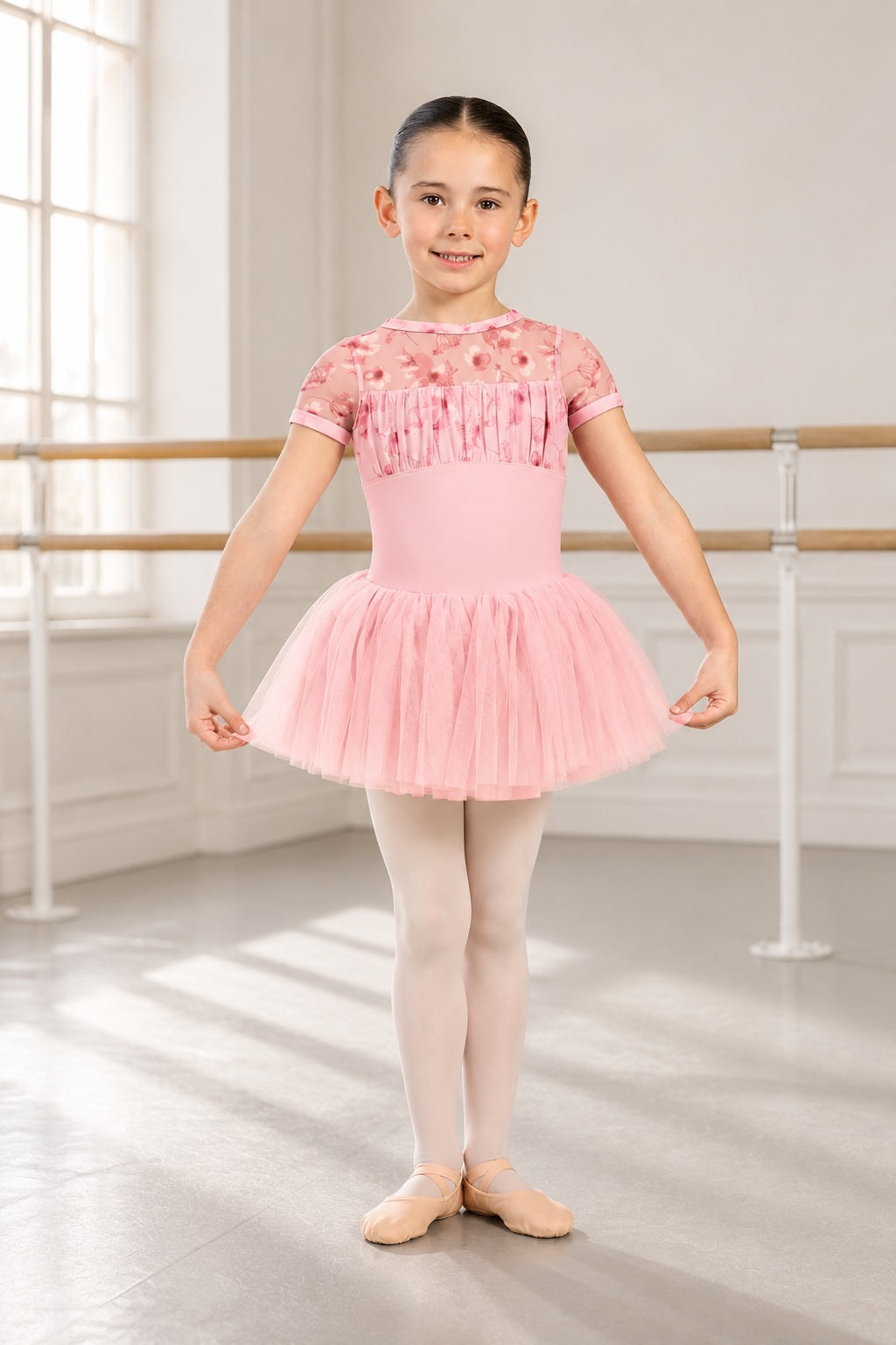 Girl wearing Bloch CL4282 pink floral ballet tutu dress standing in a bright ballet studio