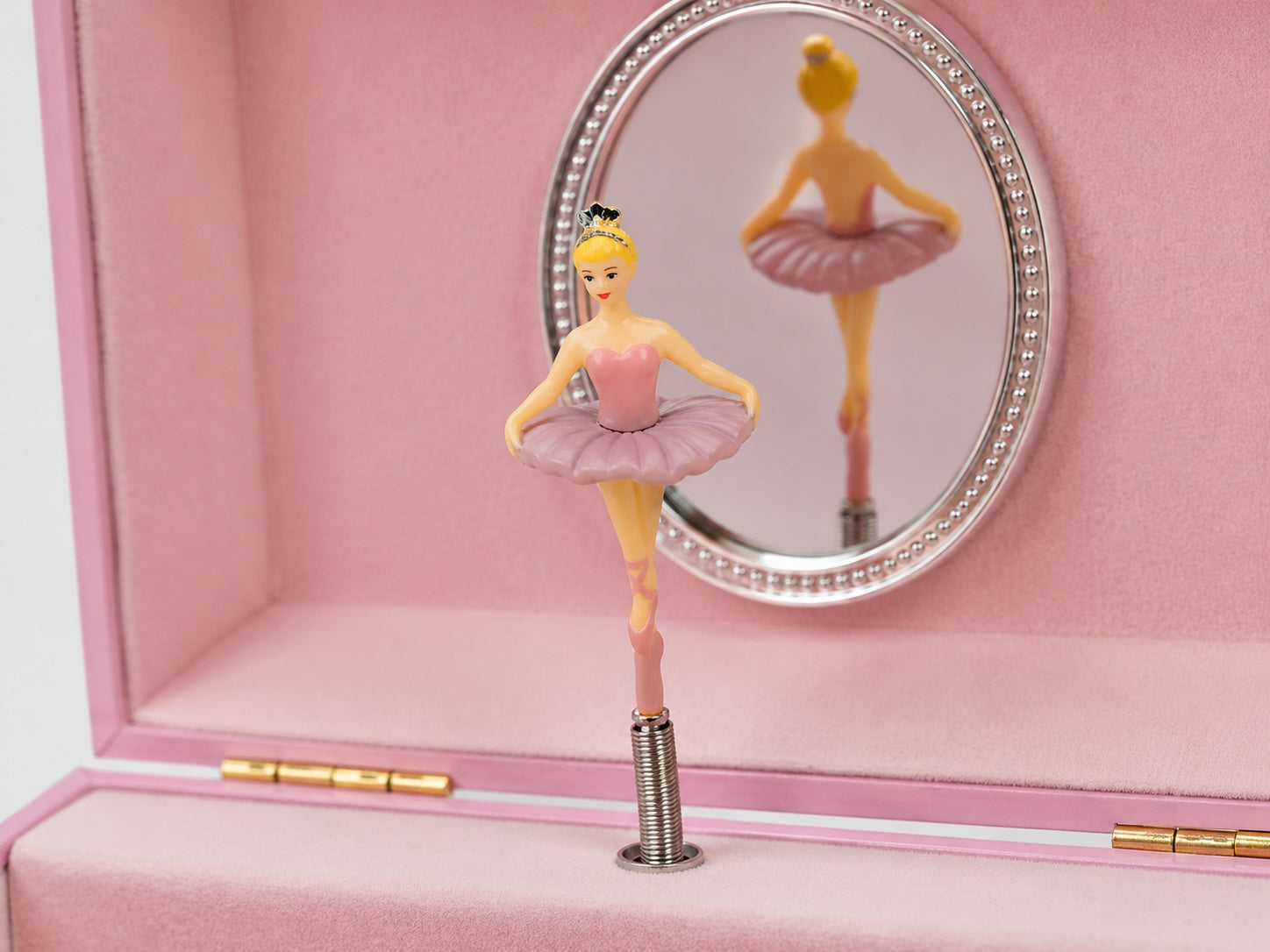 Close-up of twirling ballerina figure inside pink musical jewellery box with mirror interior