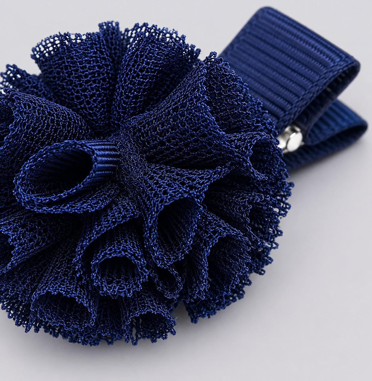 Close-up detail of navy pom pom hair clip for little dancers by Molly & Rose on light grey background