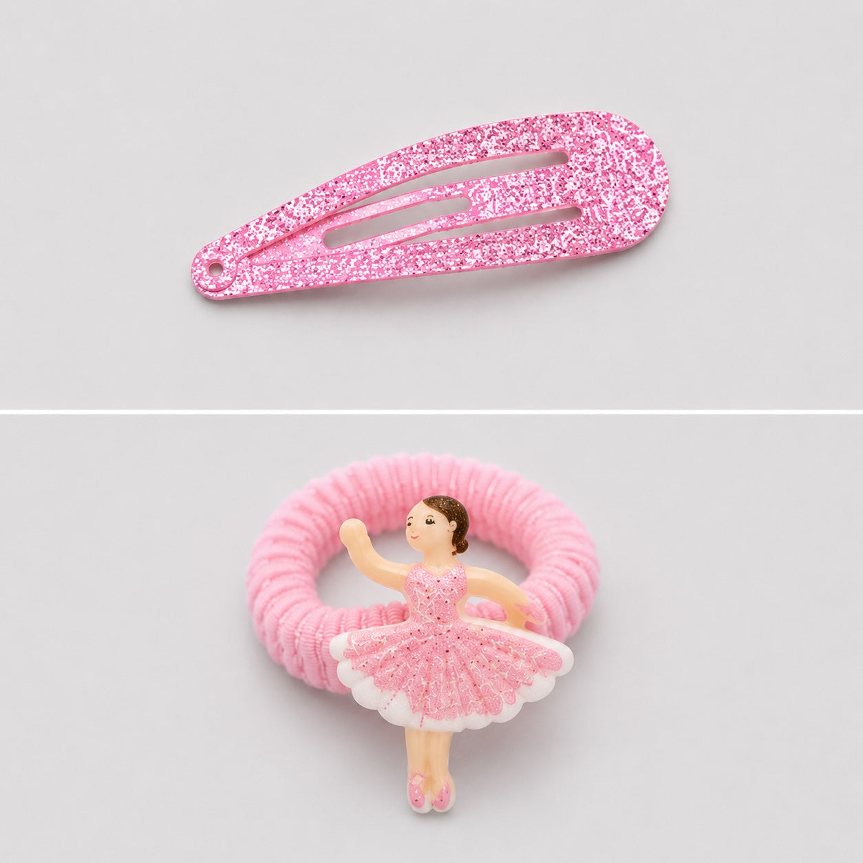 Close-up of pink glitter ballet hair clip and ballerina ponytail holder on light grey background