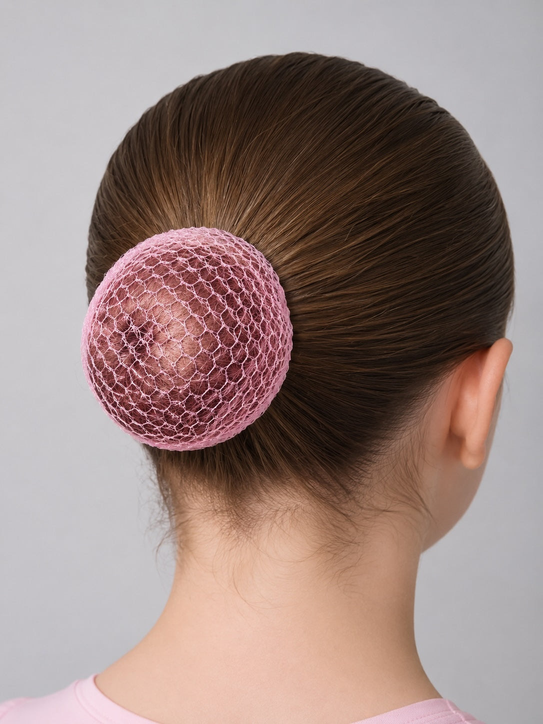 Back view of ballet bun styled with pink hair net for dance class and performances