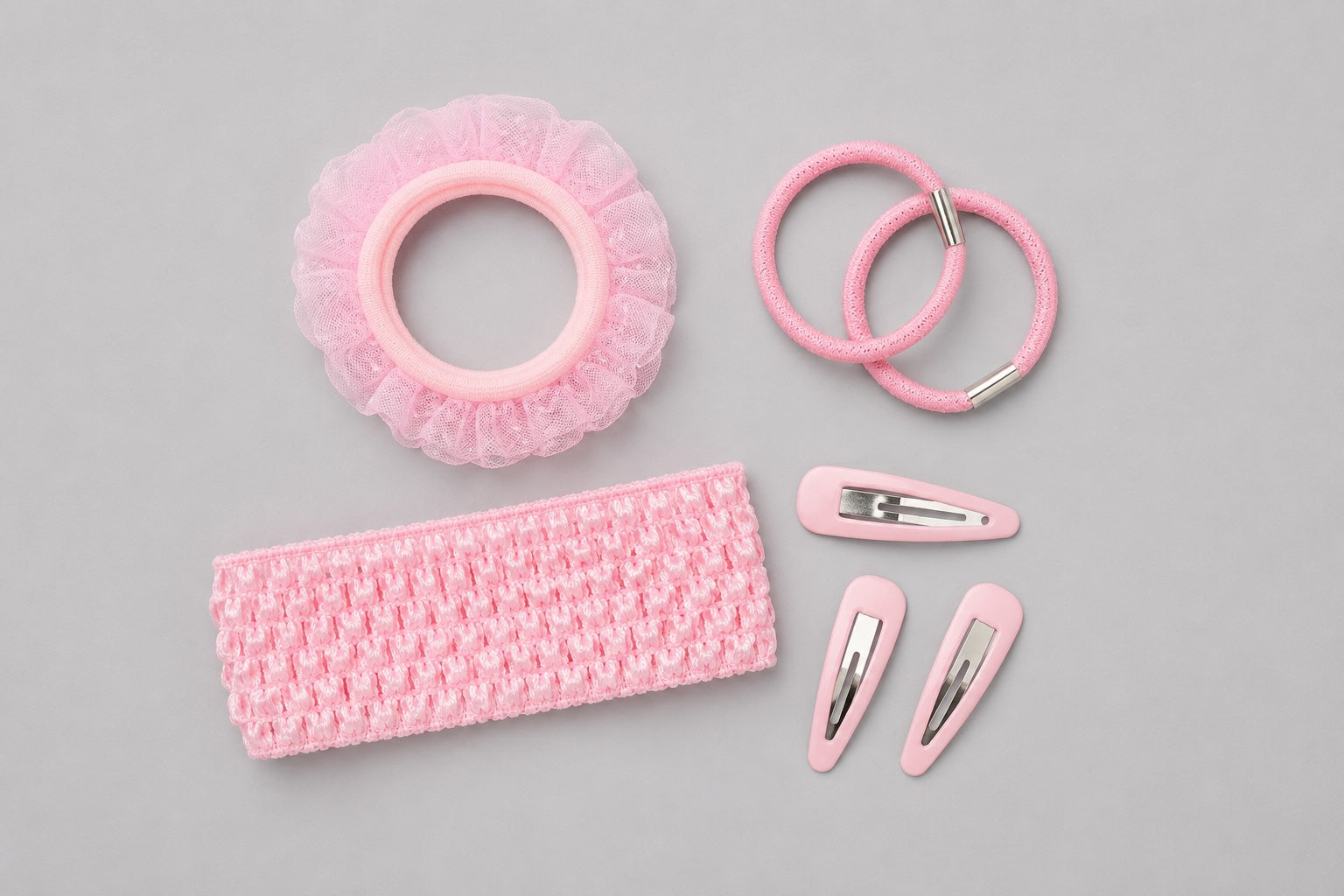 Pink ballet hair accessories flat lay with clips, headband and elastics on light grey background