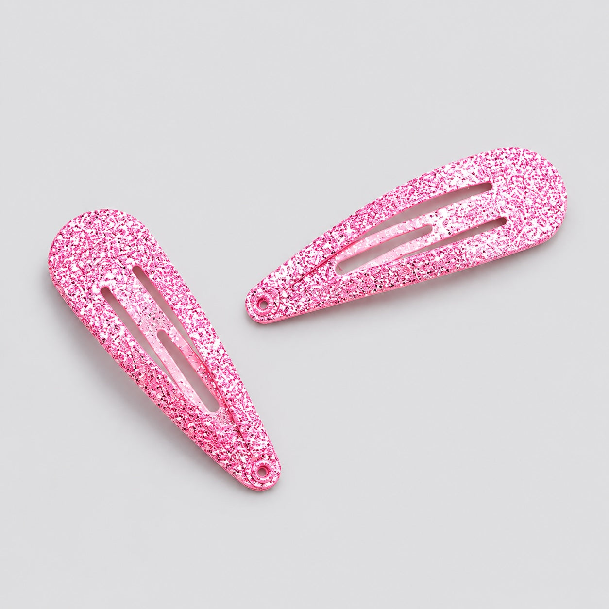 Close-up of pink glitter ballet hair clips on light grey background